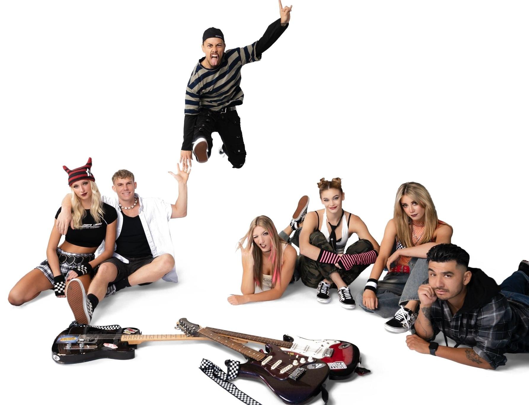 Punk Rock Brunch cast lounging around electric guitars as one performer jumps with rock horns